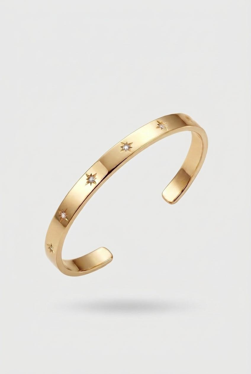 Gold bracelet with star designs on a light gray background