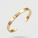 Gold bracelet with star designs on a light gray background