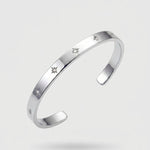 Silver bracelet with engraved stars on a light gray background