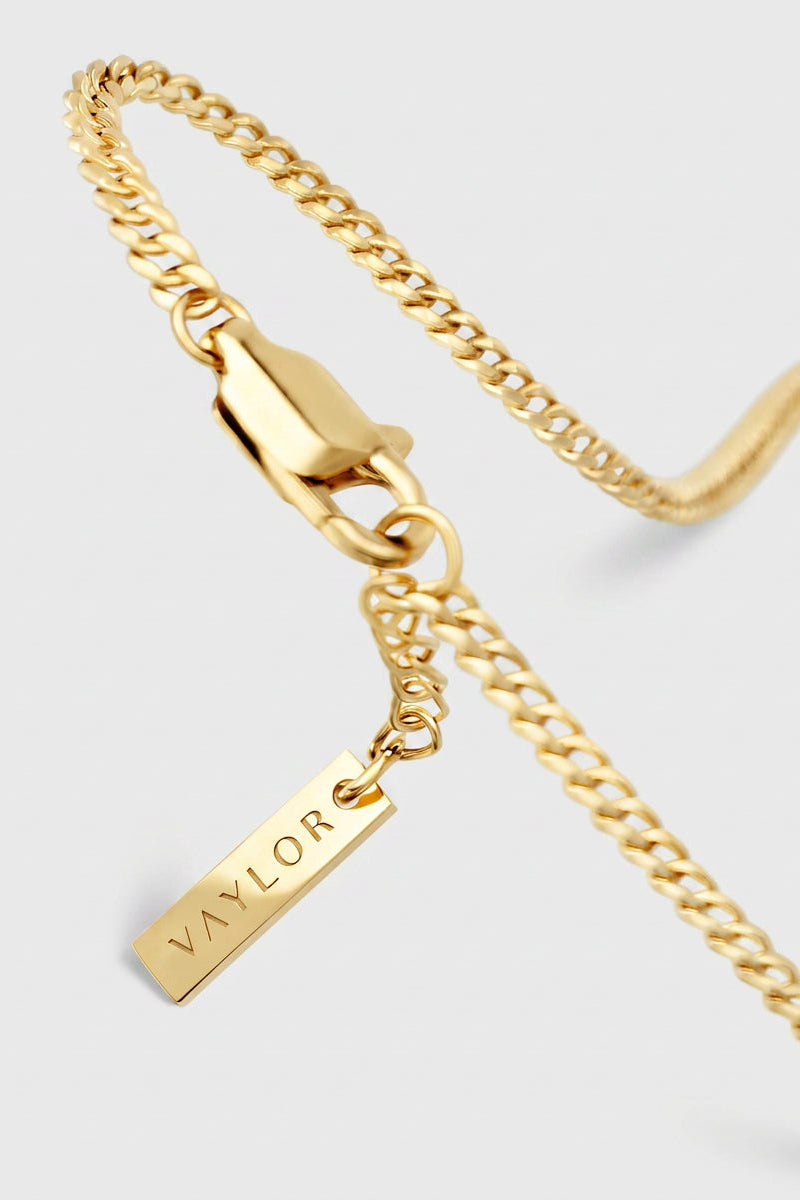 Gold chain necklace with a tag pendant on a light gray background