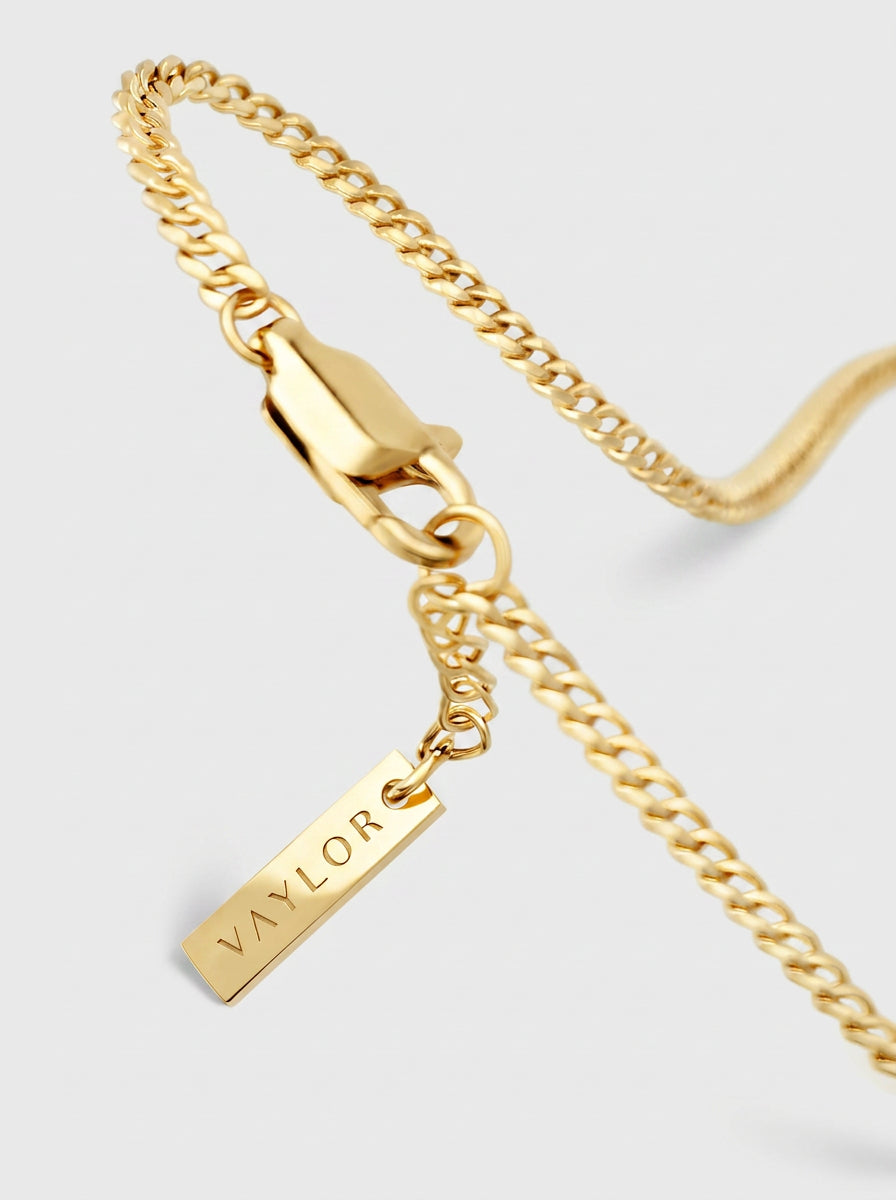Gold chain necklace with a tag pendant on a light gray background