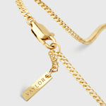 Gold chain necklace with a tag pendant on a light gray background