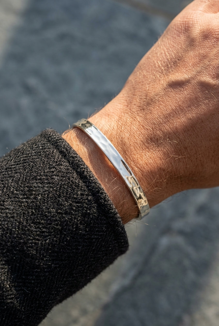 Close-up of a wrist wearing a silver and brown bracelet against a blurred background