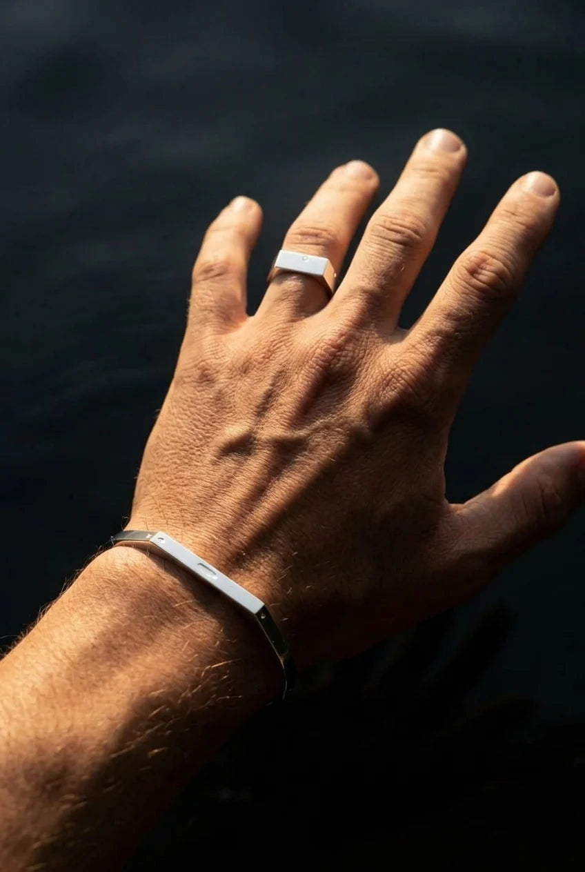 Hand with a silver ring against a dark background