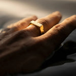 Gold ring on a person's finger with a blurred background