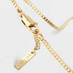 Gold bracelet with a tag on a light gray background