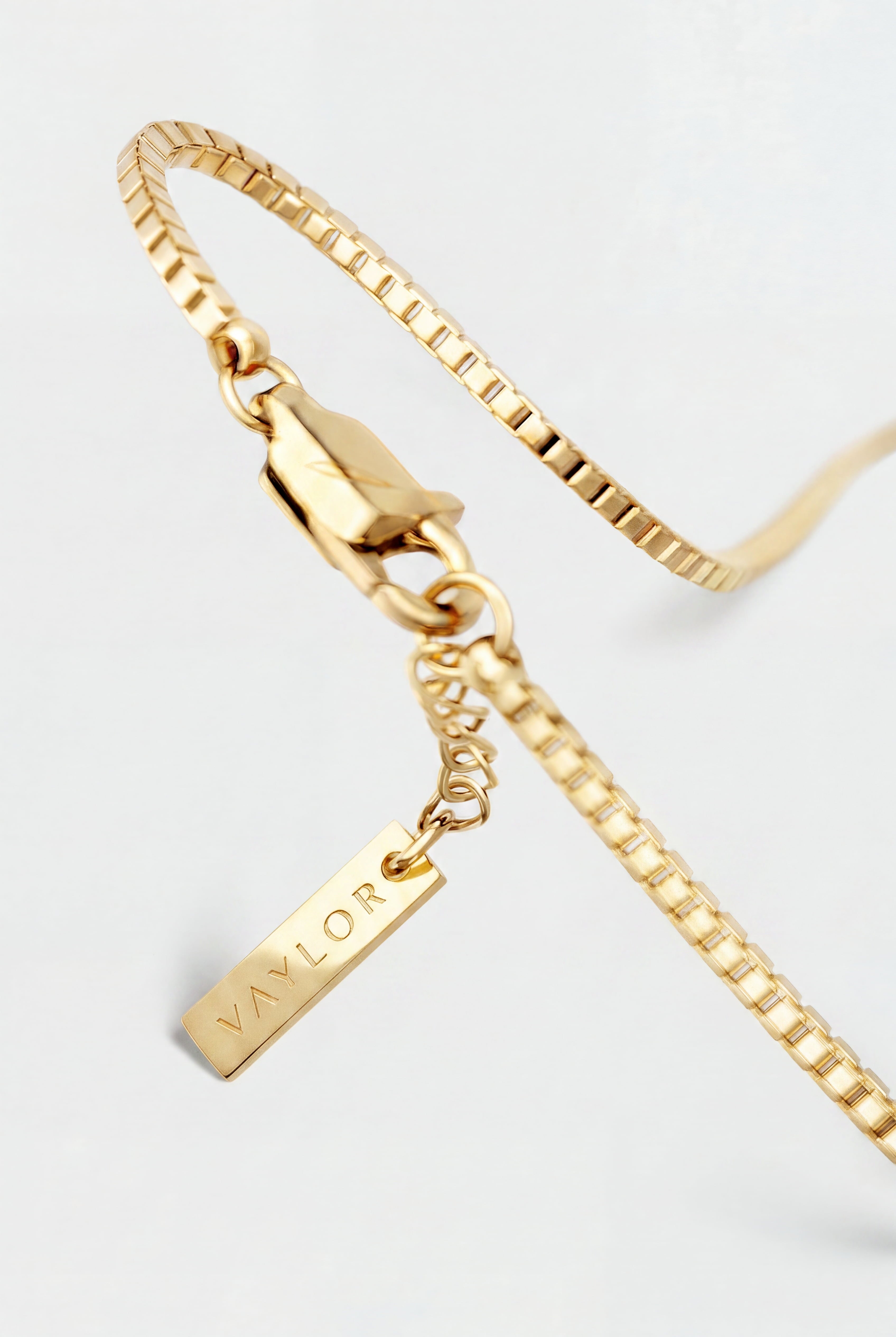 Gold bracelet with a tag on a light gray background