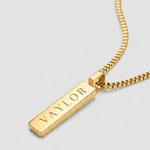Gold necklace with a bar pendant on a light gray background