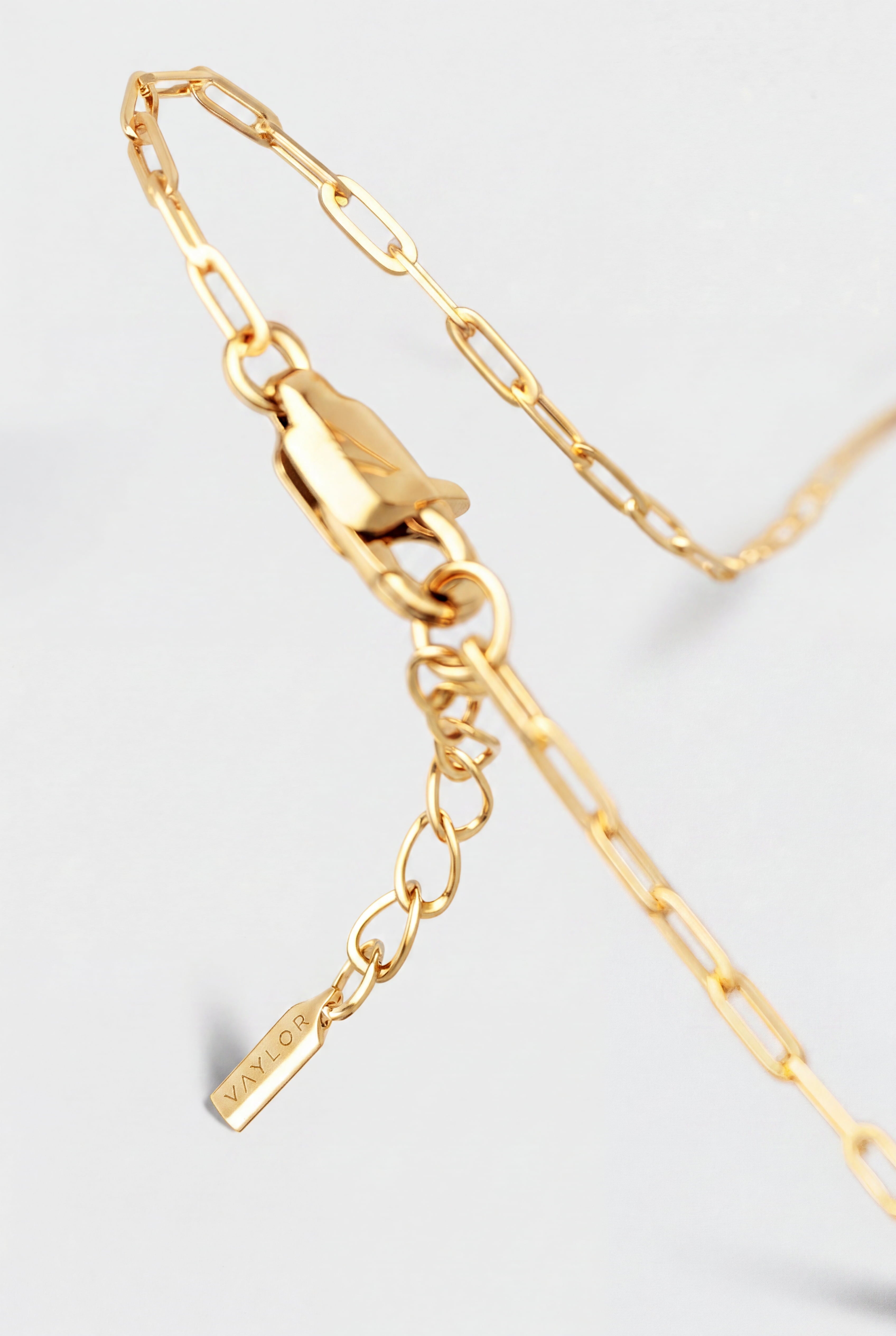 Gold bracelet with a tag on a light gray background