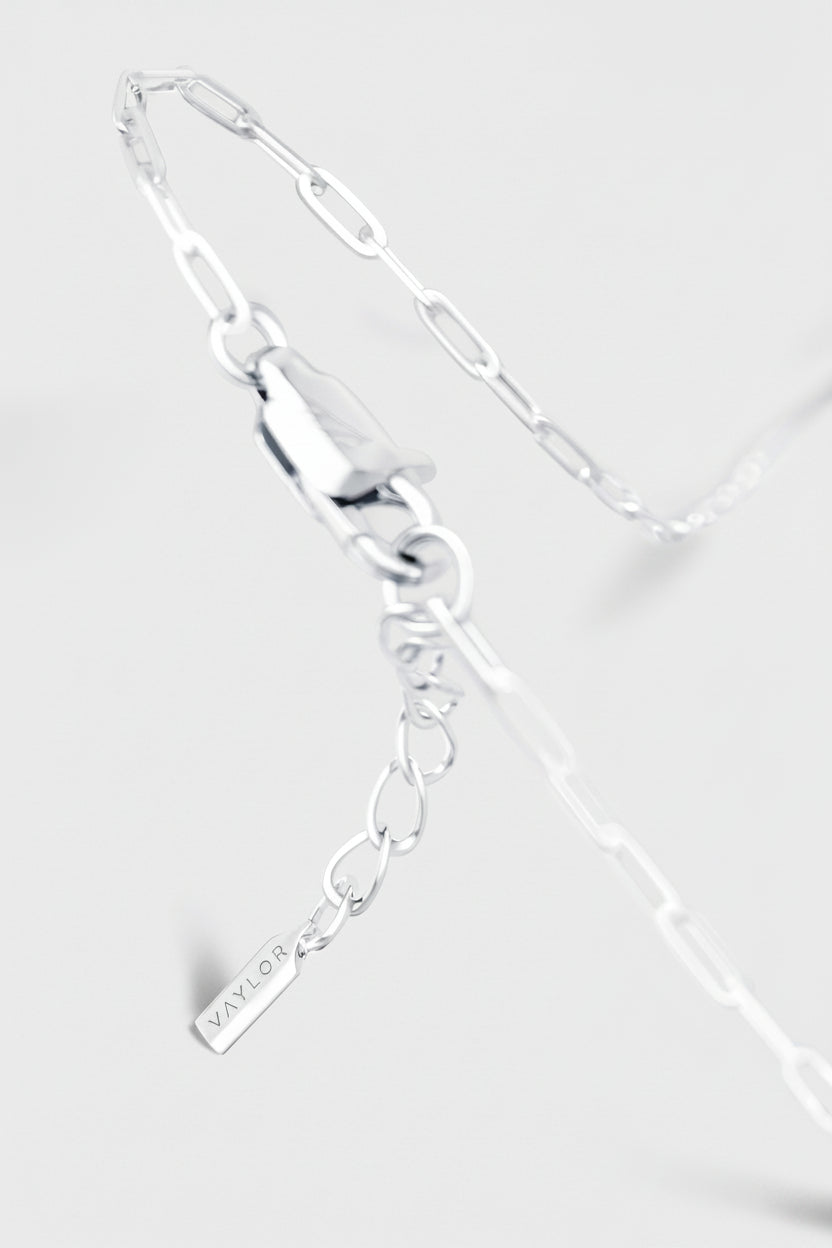 Silver bracelet with a tag on a light gray background