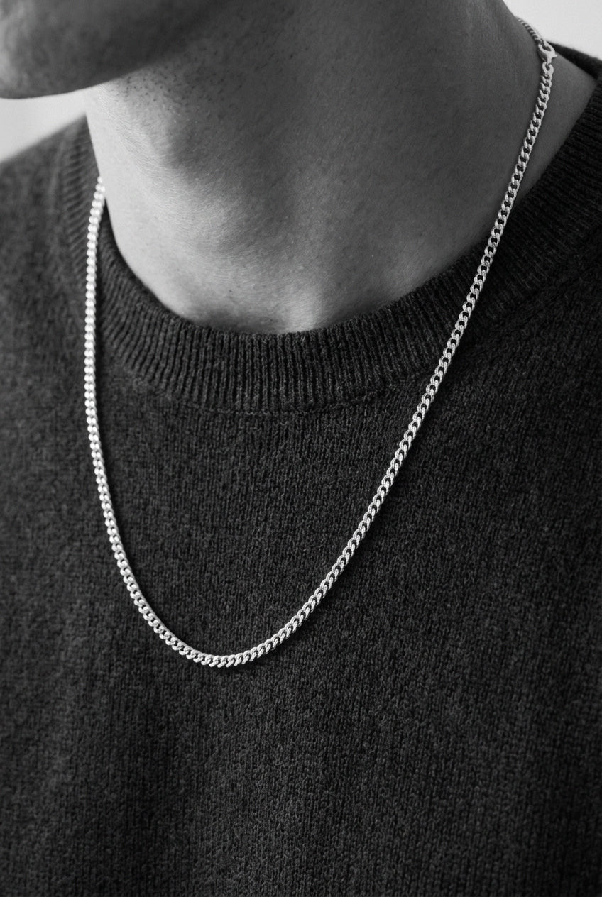 Person wearing a silver chain necklace against a black background