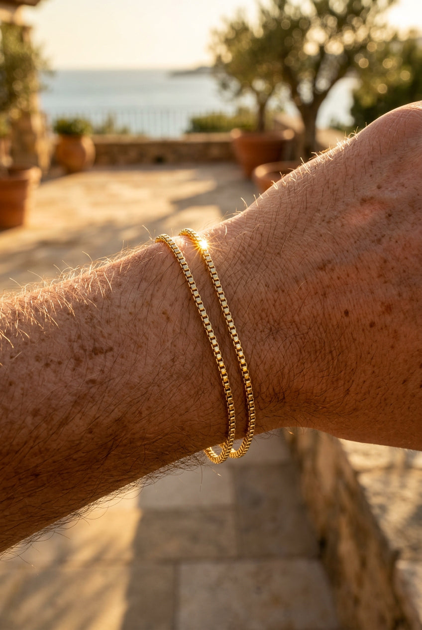 Close-up of a person's arm wearing gold bracelets with a scenic background.