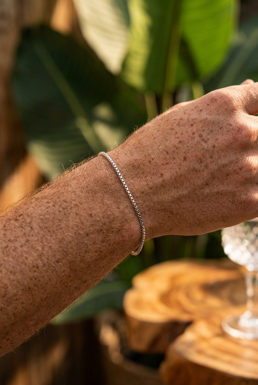 Close-up of a person's wrist wearing a silver bracelet with a blurred natural background