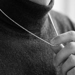 Person wearing a black turtleneck sweater with a blurred background