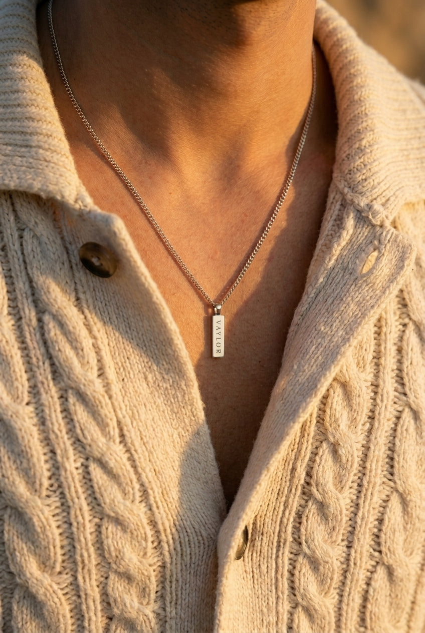 Necklace with a pendant worn by a person in a textured beige cardigan.