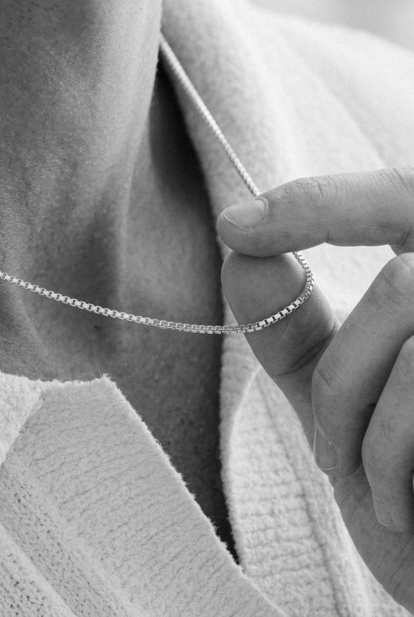 Close up photo of a mens neck holding a necklace