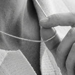 Close up photo of a mens neck holding a necklace