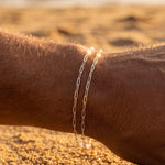 Silver chain bracelet on a wrist with a blurred beach background