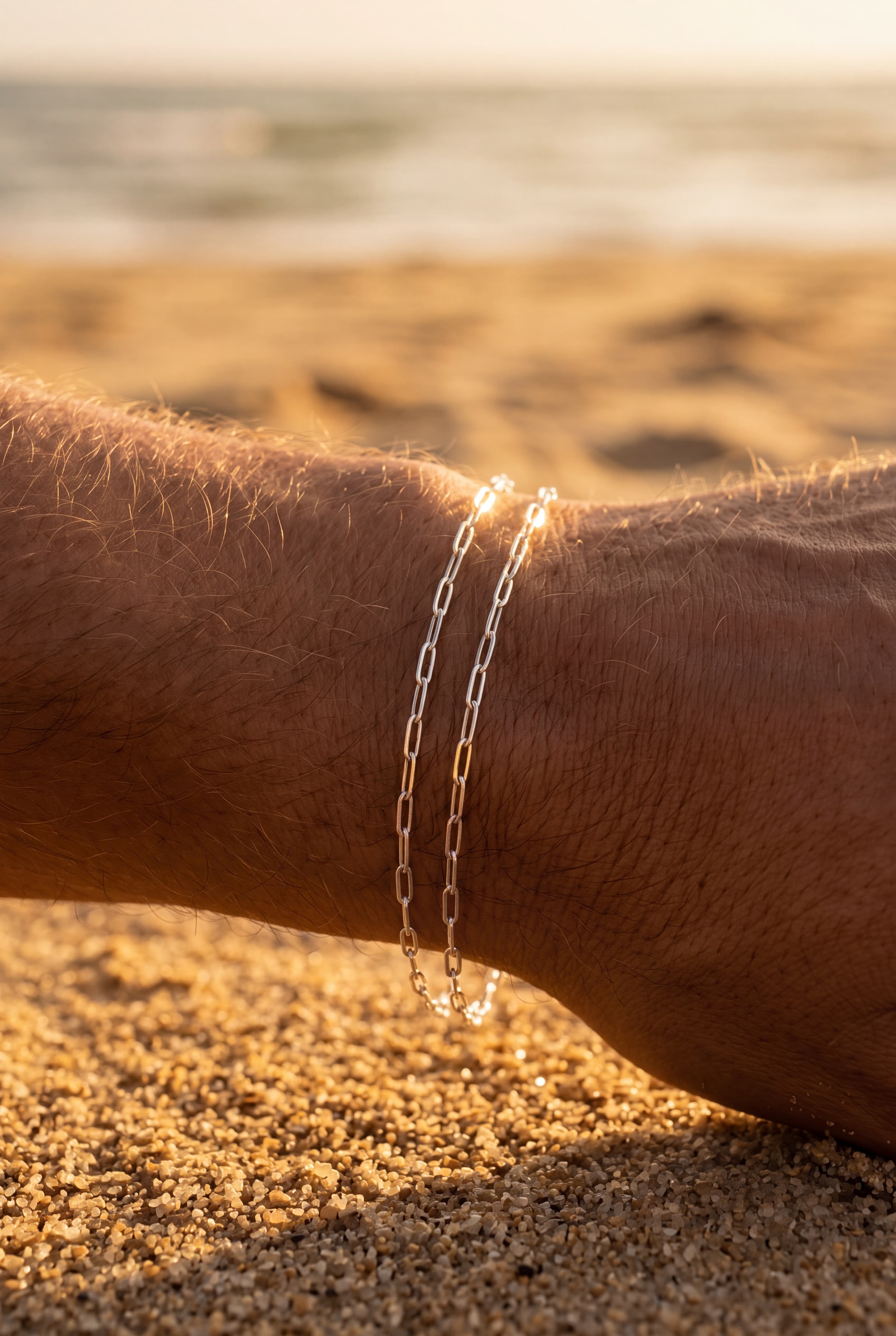 Silver chain bracelet on a wrist with a blurred beach background