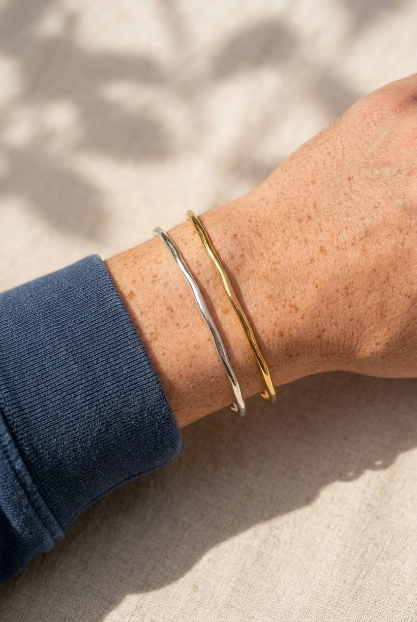Close-up of a wrist wearing two bracelets on a neutral background