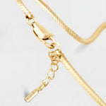 Gold bracelet with a small tag on a light gray background
