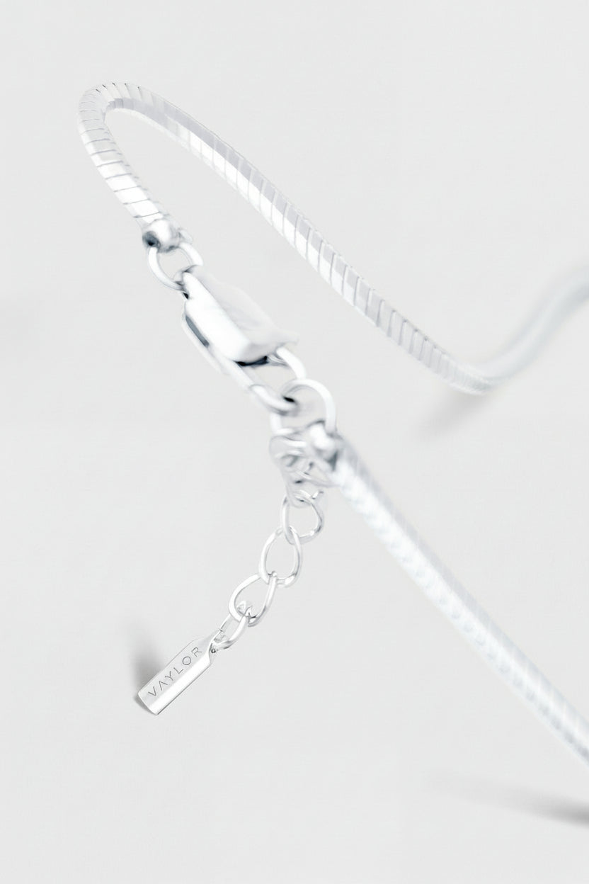 Silver bracelet with a tag on a light gray background