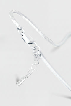 Silver bracelet with a tag on a light gray background