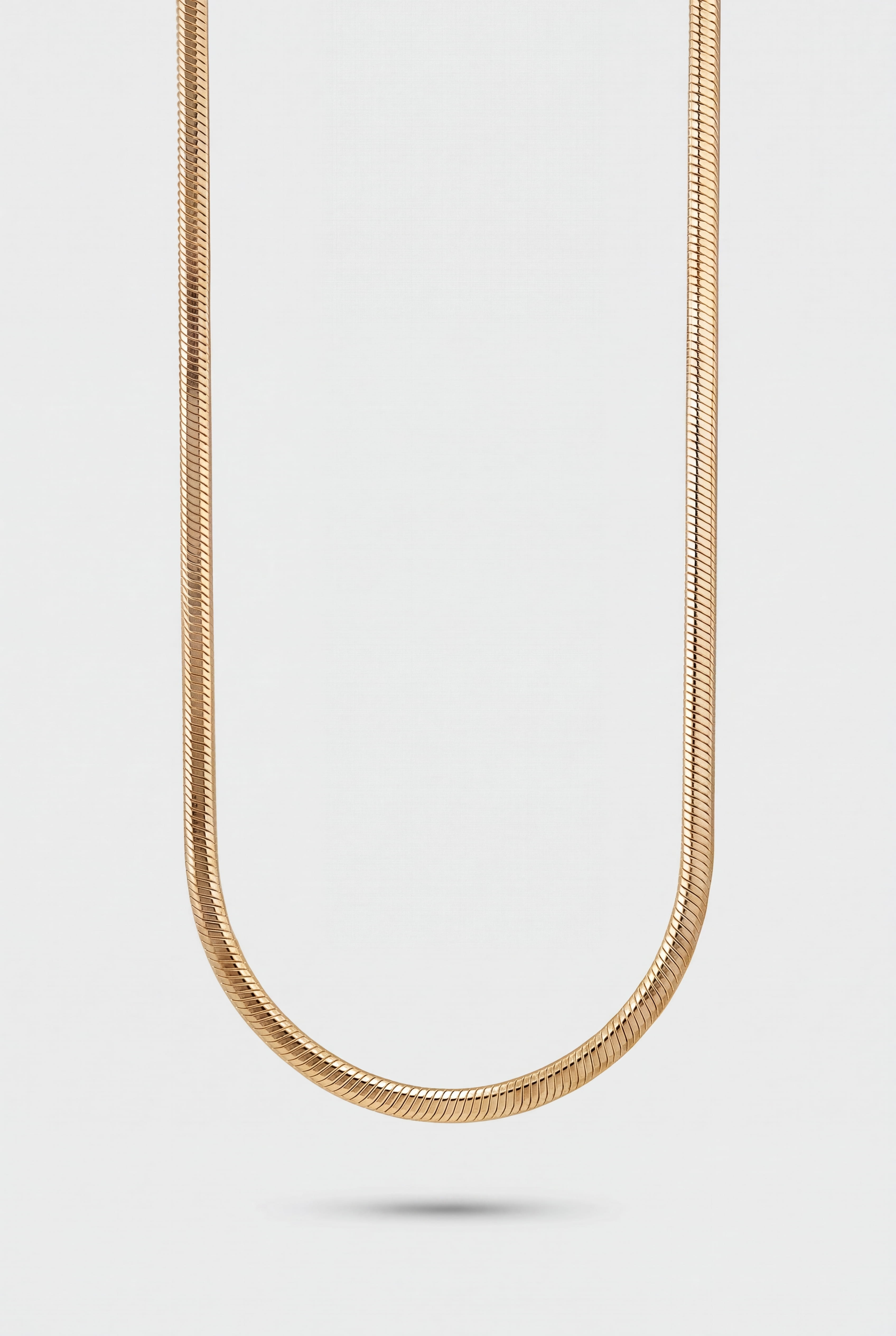 Gold chain necklace on a light gray background