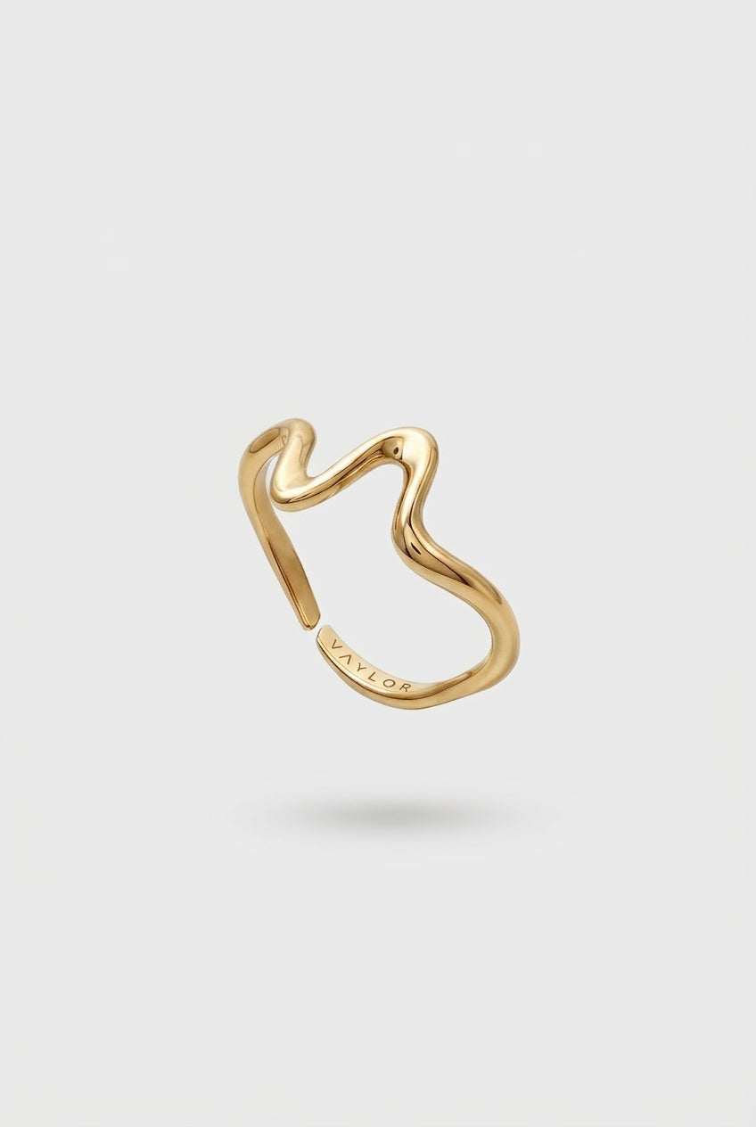 Gold wave shaped ring on a light gray background