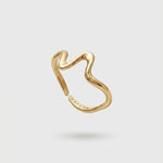 Gold wave shaped ring on a light gray background