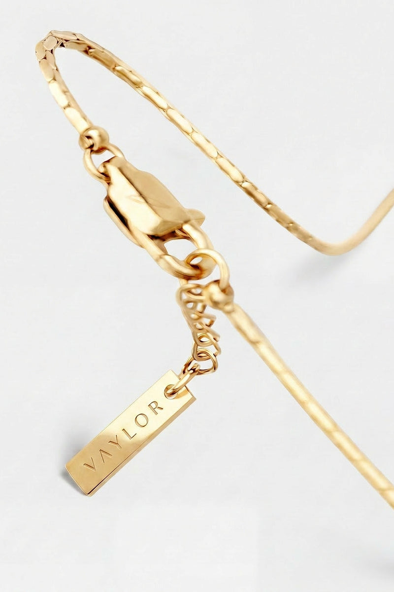 Gold bracelet with a tag on a light gray background
