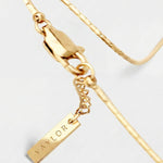 Gold bracelet with a tag on a light gray background