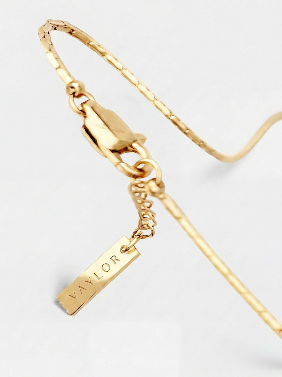 Gold bracelet with a tag on a light gray background