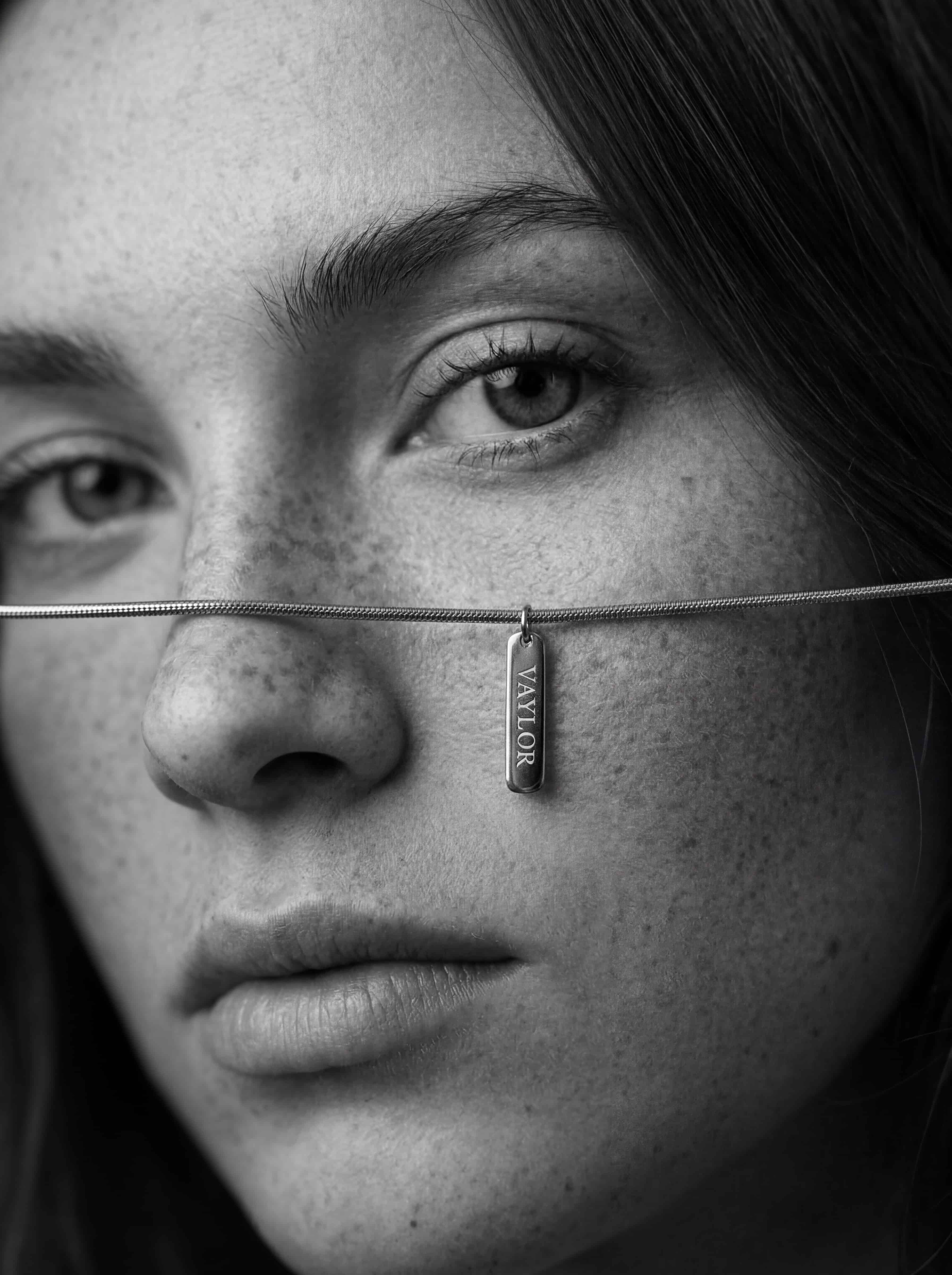 Close-up of a woman's face with a necklace featuring a pendant.
