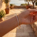 Hand with bracelets on a stone pathway with a scenic background