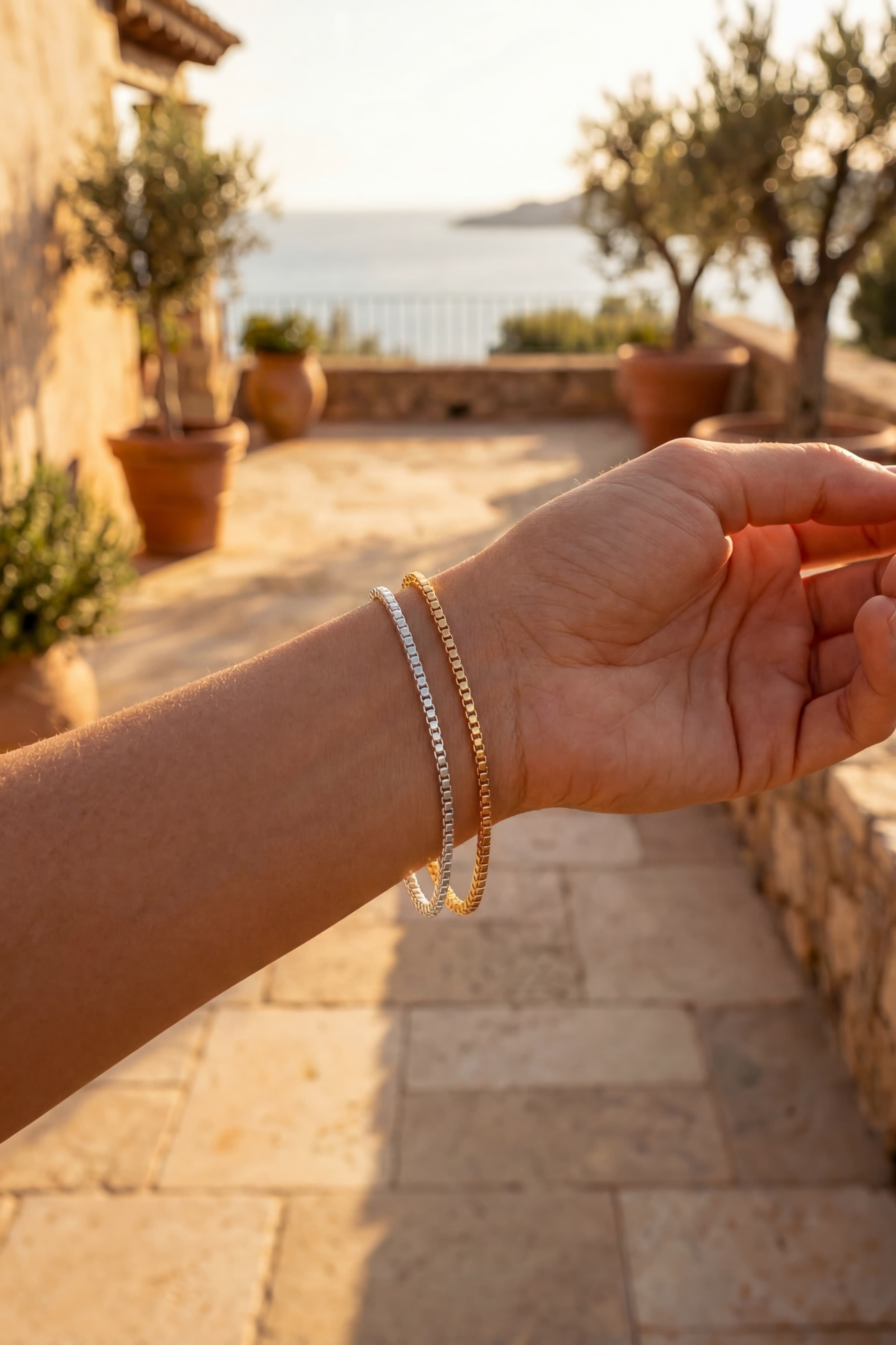 Hand with bracelets on a stone pathway with a scenic background