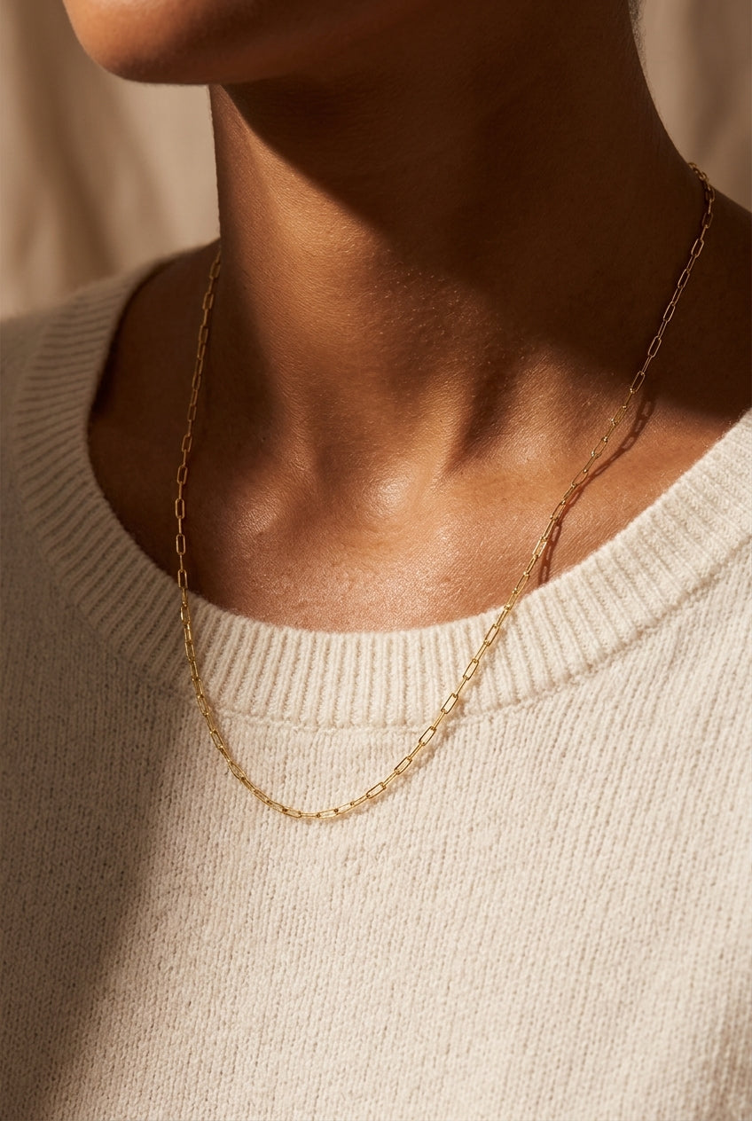 Gold chain necklace worn by a person in a beige sweater