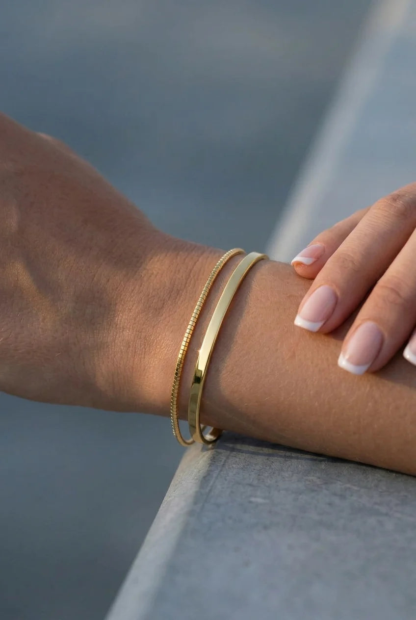 Gold bracelets on a wrist with a blurred background