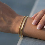 Gold bracelets on a wrist with a blurred background