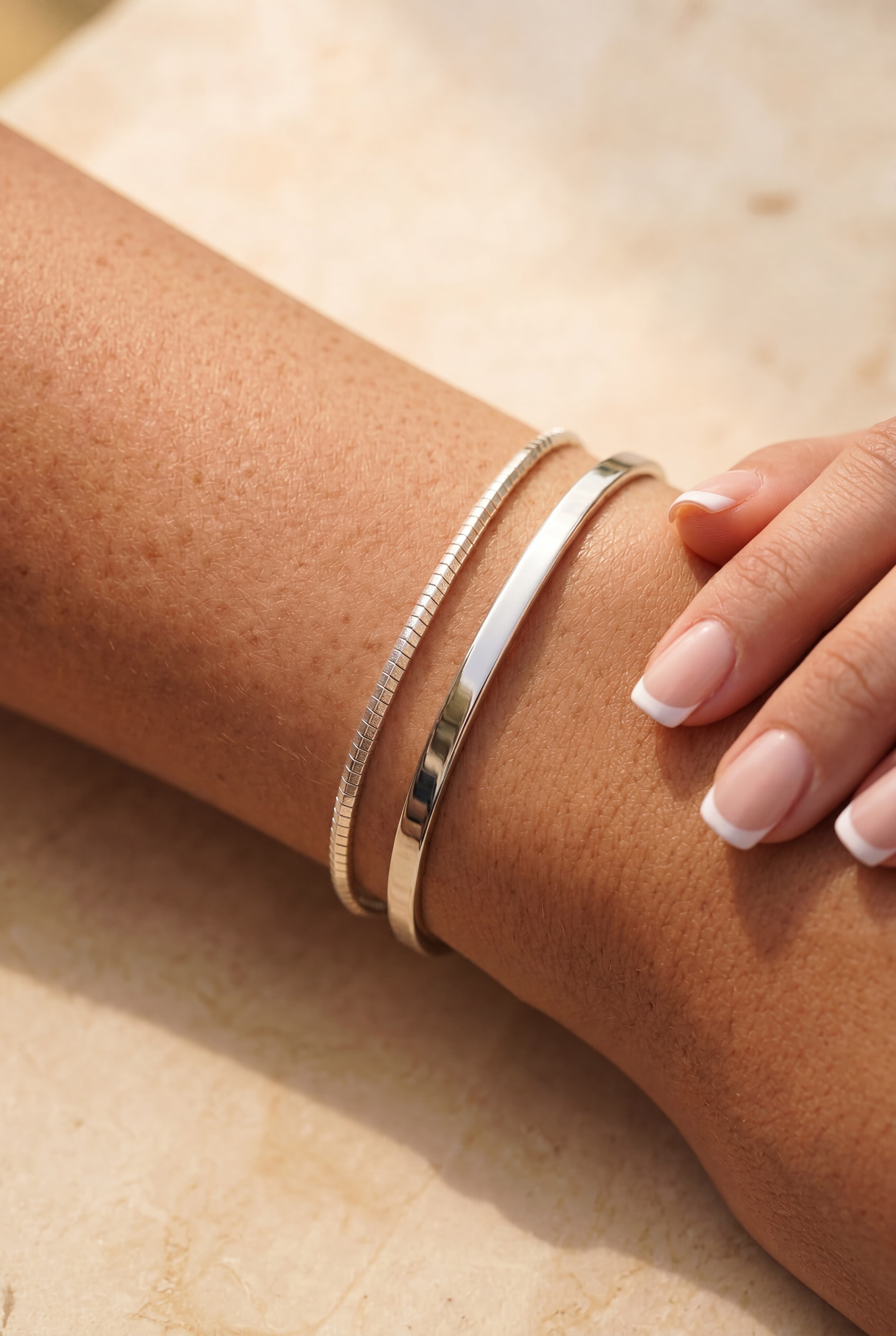 Womens arm with a cuff bangle and a bracelet in silver 