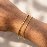 Gold bracelet on a person's wrist with a neutral background