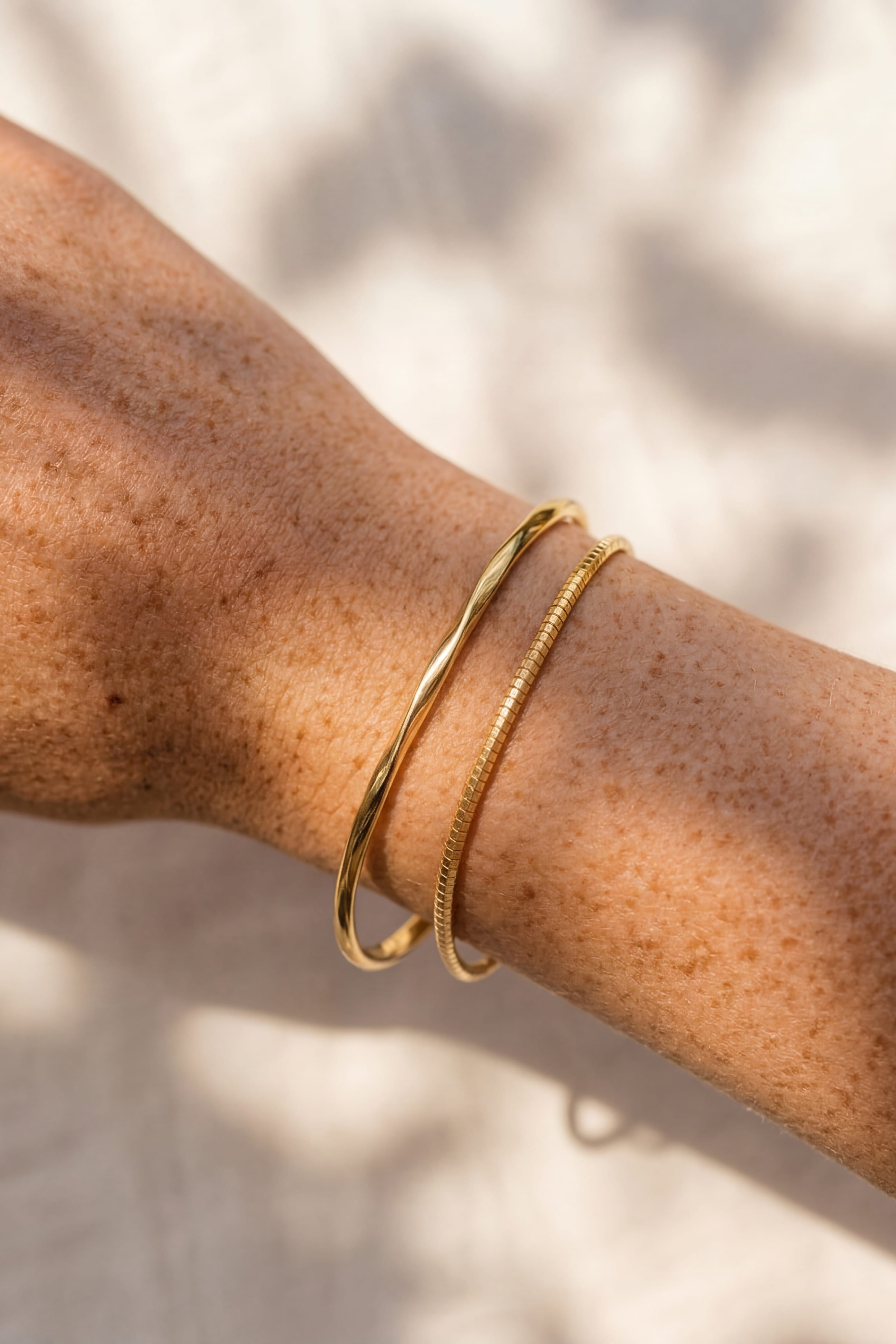 Gold bracelet on a person's wrist with a neutral background