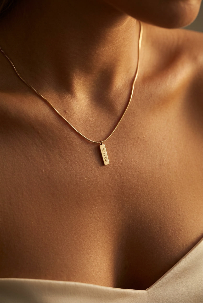 Gold necklace with a pendant on a person's neck