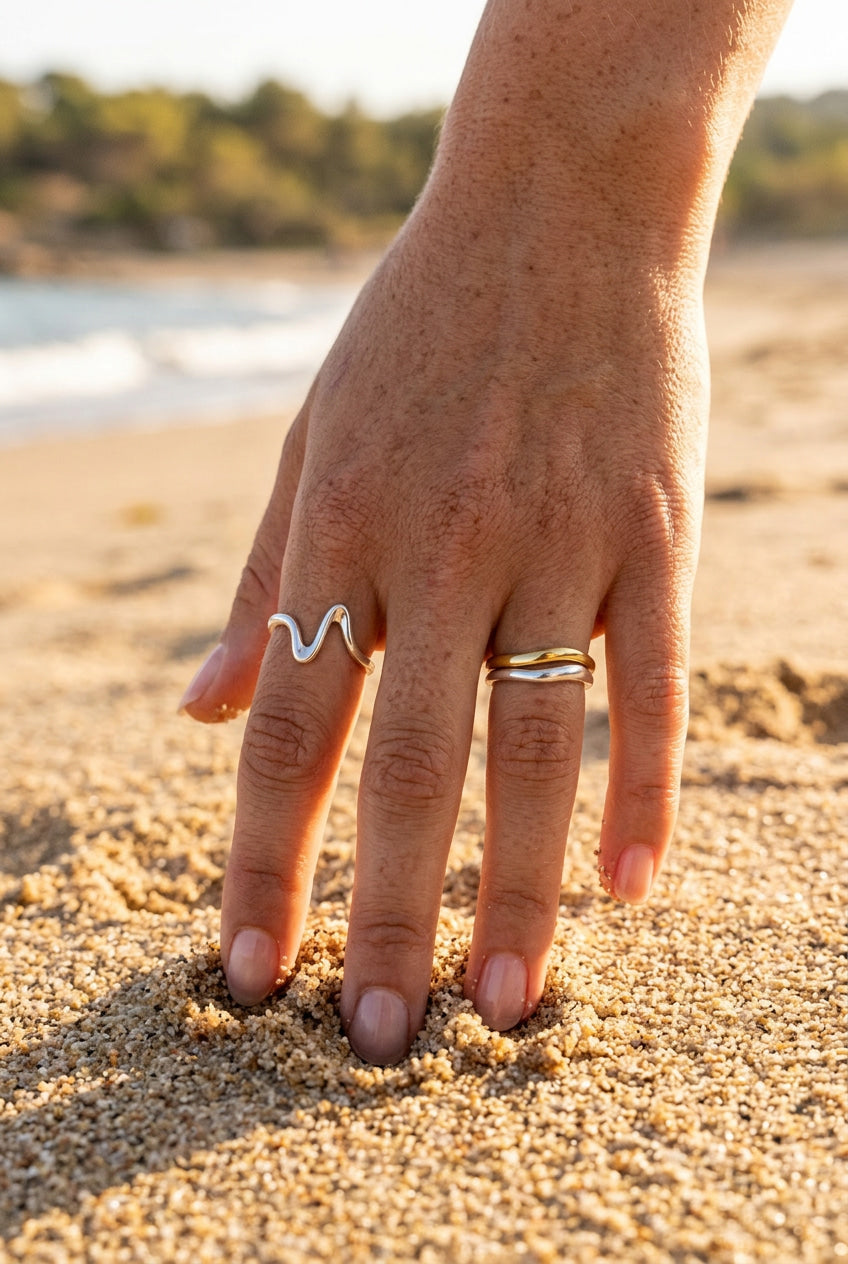 Hand with two rings on a sandy beach