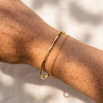 Gold bracelet on a person's wrist with a neutral background