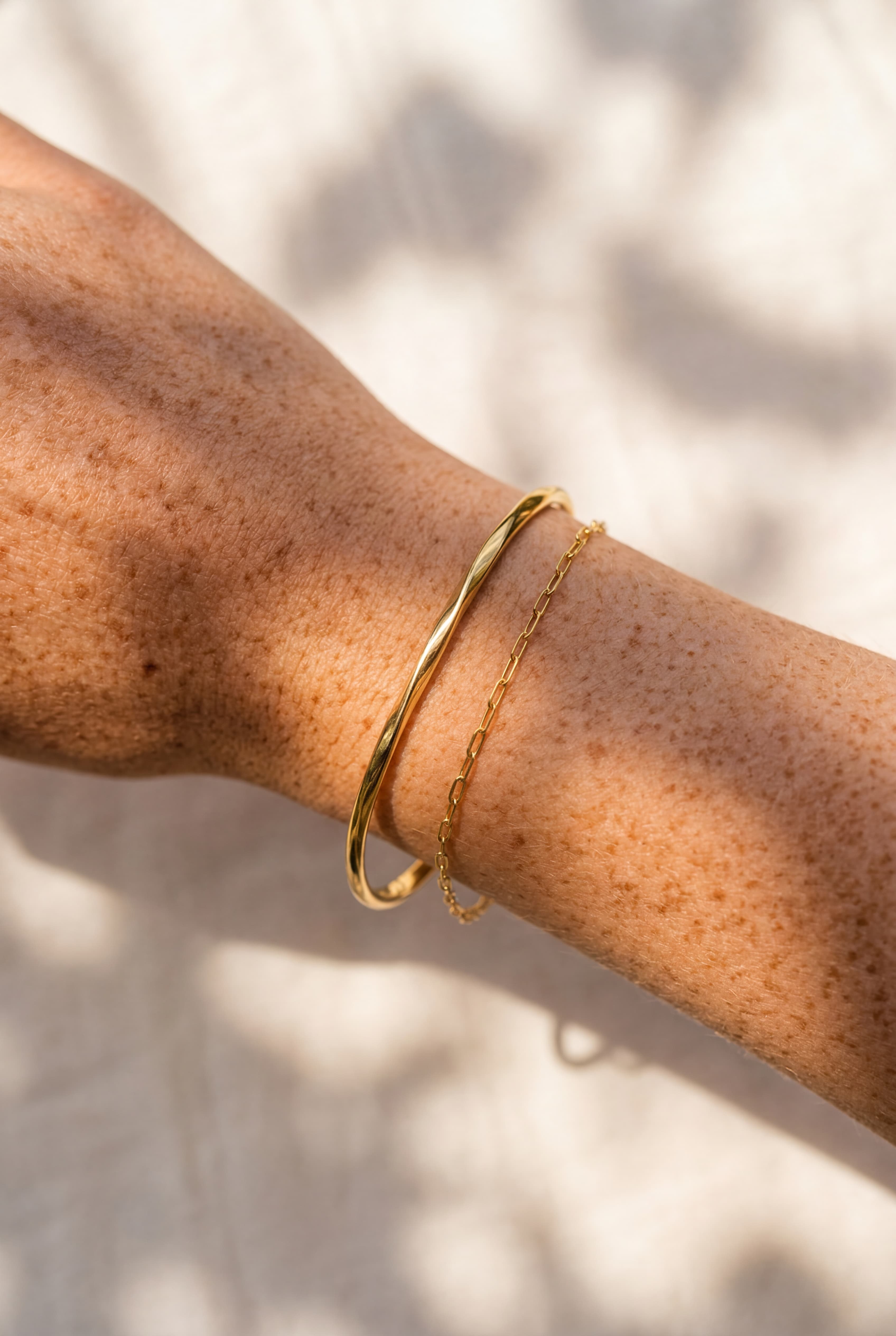 Gold bracelet on a person's wrist with a neutral background