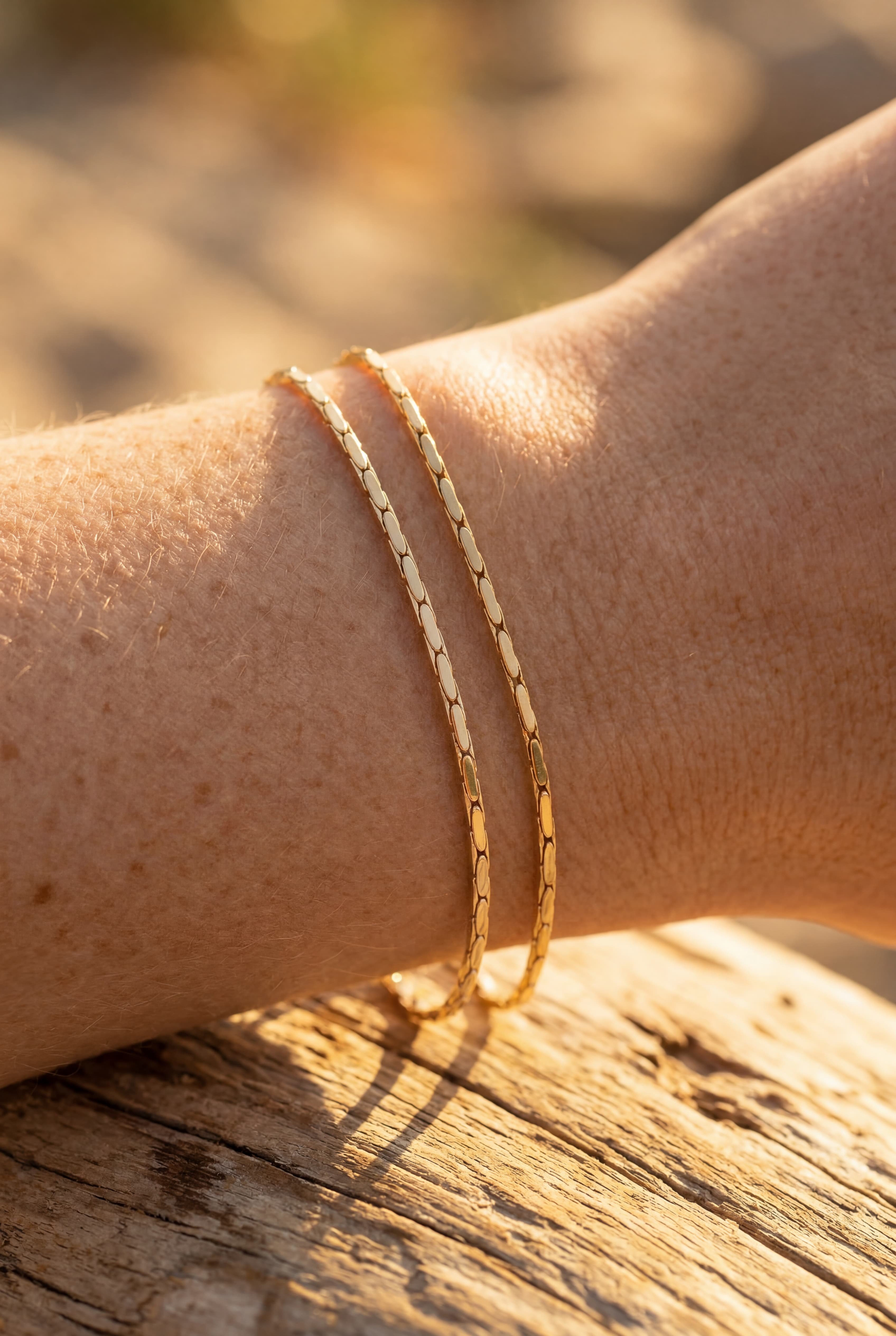 Gold bracelet on a wrist with a blurred natural background